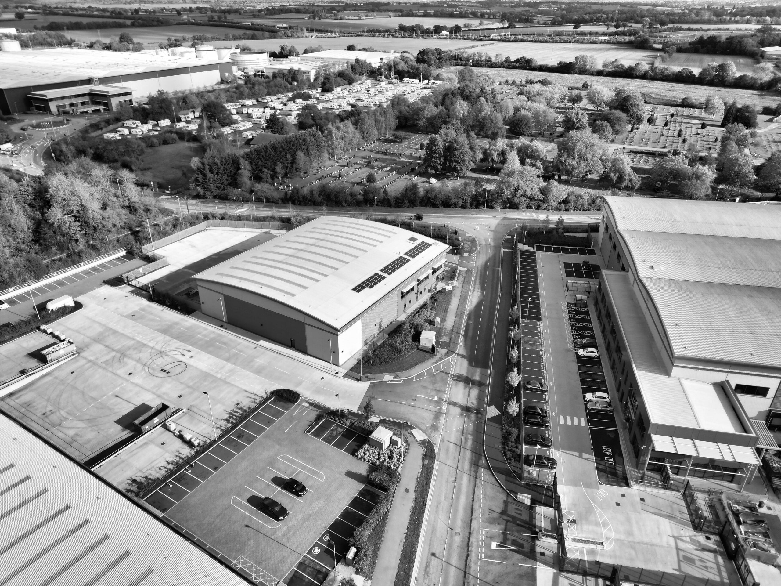 Black and white aerial photo of industrial buildings and parking in Hertfordshire, England.